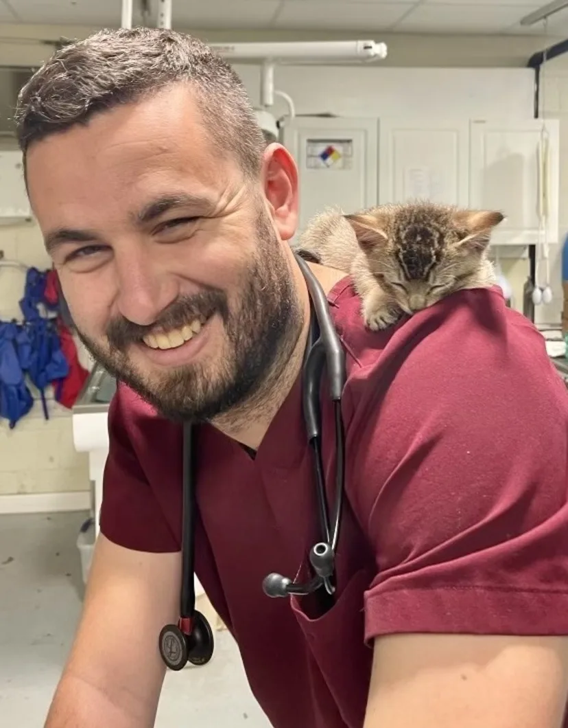 Dr. John Komlosy in red scrubs and kitten on back.